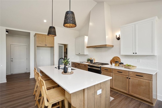 kitchen with wall chimney range hood, dark wood-style flooring, gas stove, and a sink