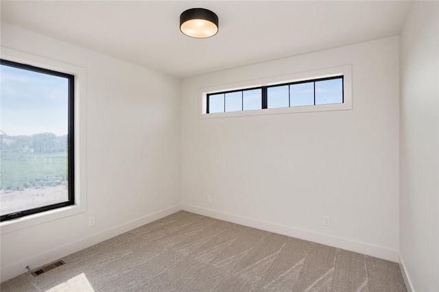 empty room with light carpet, visible vents, and baseboards