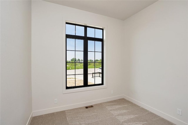 spare room featuring visible vents, baseboards, and light colored carpet