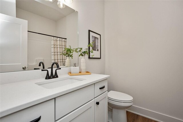 bathroom featuring toilet, a shower with shower curtain, wood finished floors, vanity, and baseboards