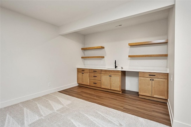 interior space featuring visible vents, dark wood-type flooring, built in study area, a sink, and baseboards