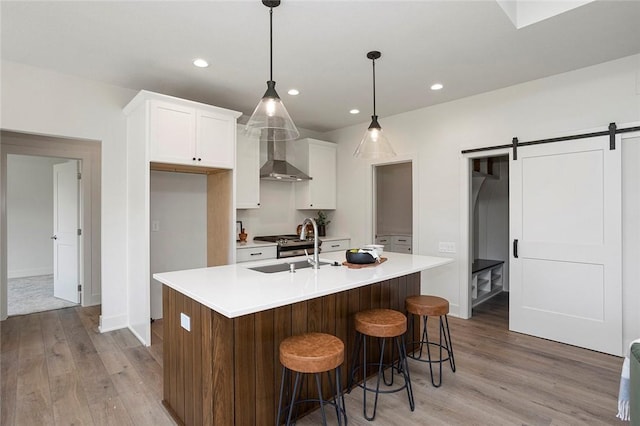 kitchen with white cabinets, a barn door, a center island with sink, and hanging light fixtures