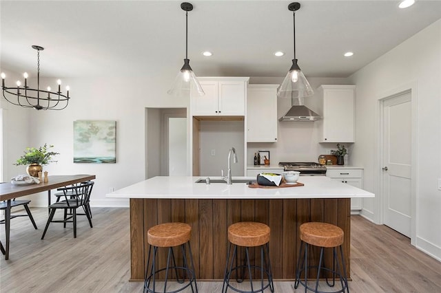 kitchen featuring sink, a notable chandelier, a breakfast bar, white cabinets, and a center island with sink