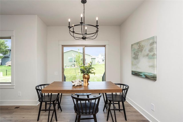 dining area with dark wood-type flooring, a healthy amount of sunlight, and an inviting chandelier