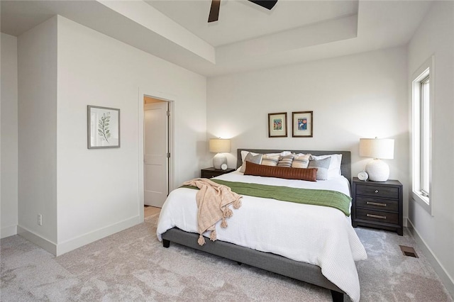 carpeted bedroom with a tray ceiling and ceiling fan