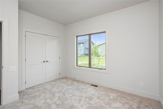 unfurnished bedroom featuring light carpet and a closet