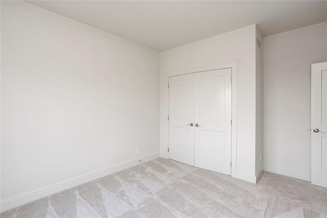 unfurnished bedroom featuring light carpet and a closet