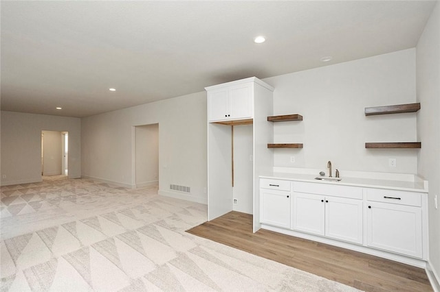 kitchen featuring light colored carpet, white cabinetry, and sink