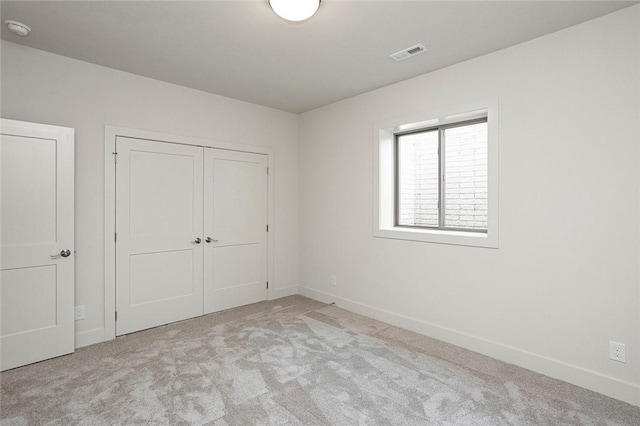 unfurnished bedroom with light colored carpet and a closet