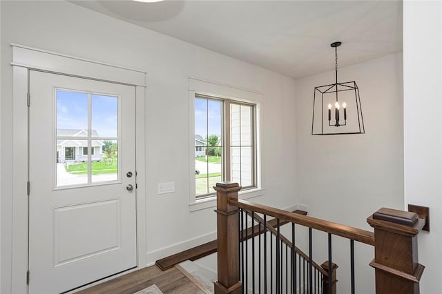 doorway to outside featuring hardwood / wood-style flooring, a wealth of natural light, and a chandelier