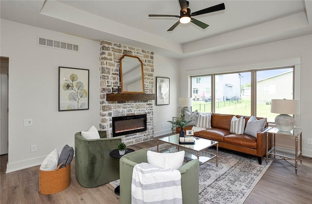 living room with ceiling fan, a raised ceiling, and plenty of natural light