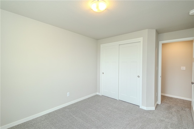 unfurnished bedroom featuring a closet and light carpet