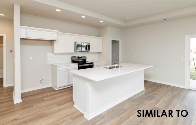 kitchen with a kitchen island with sink, sink, appliances with stainless steel finishes, white cabinets, and light hardwood / wood-style floors