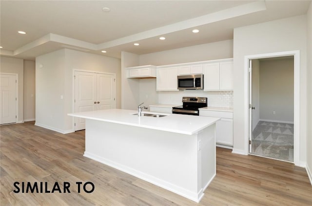 kitchen featuring white cabinetry, stainless steel appliances, a center island with sink, and light hardwood / wood-style floors