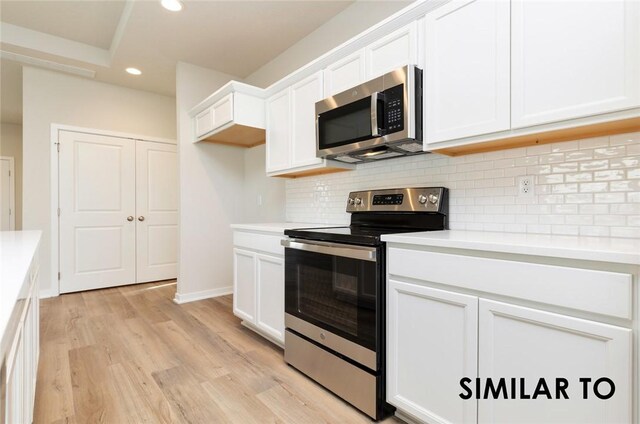 kitchen with light hardwood / wood-style flooring, stainless steel appliances, white cabinets, and decorative backsplash