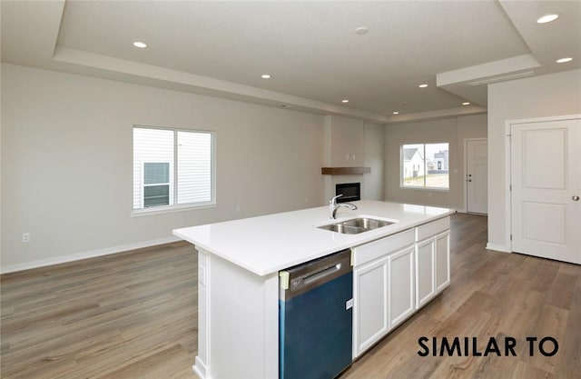 kitchen with an island with sink, dishwasher, sink, and light wood-type flooring