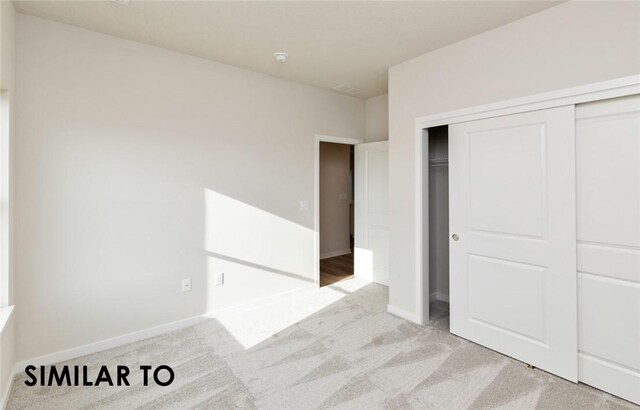 unfurnished bedroom with light colored carpet and a closet