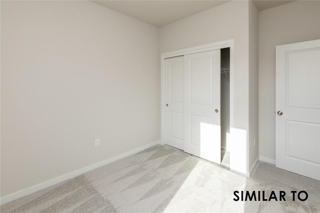 unfurnished bedroom featuring light carpet and a closet