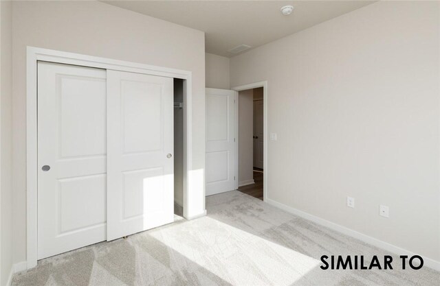 unfurnished bedroom featuring light colored carpet and a closet