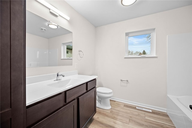 full bathroom featuring a wealth of natural light, toilet, vanity, and hardwood / wood-style flooring