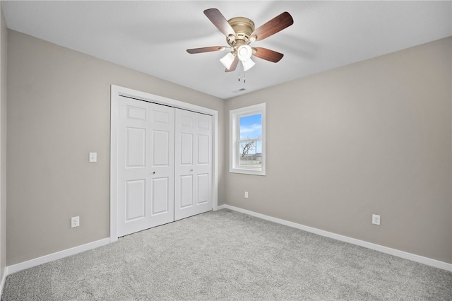 unfurnished bedroom with ceiling fan, light carpet, and a closet