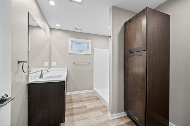 bathroom featuring vanity, wood-type flooring, and walk in shower