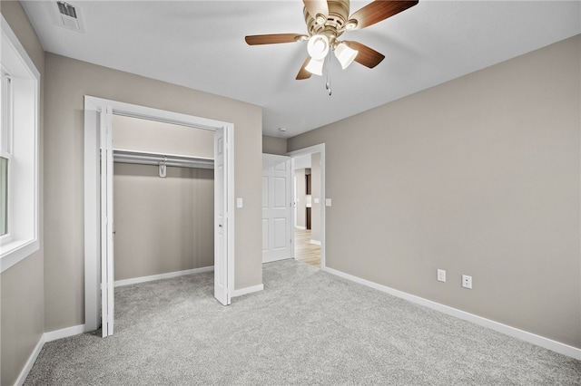 unfurnished bedroom with a closet, light colored carpet, and ceiling fan