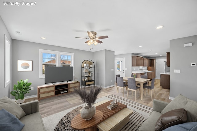 living room featuring ceiling fan and light hardwood / wood-style flooring