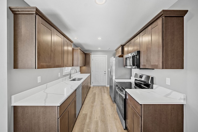 kitchen featuring light stone countertops, stainless steel appliances, light hardwood / wood-style floors, and sink