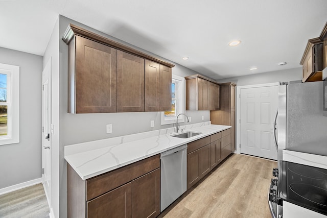 kitchen with light stone counters, light hardwood / wood-style flooring, stainless steel appliances, and sink