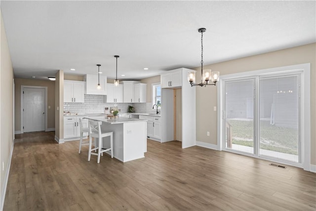 kitchen featuring white cabinets, a kitchen island, hanging light fixtures, and light wood-type flooring