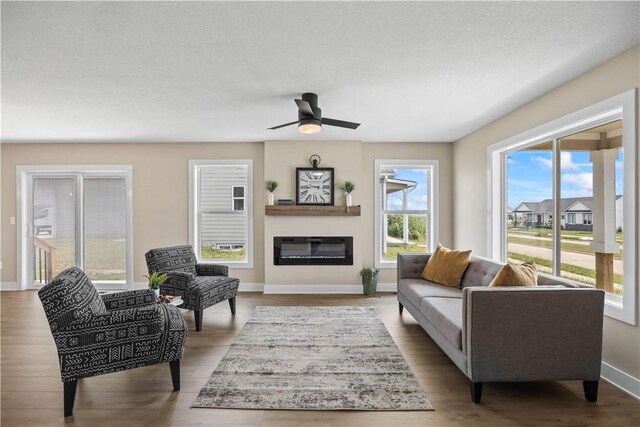 living room featuring light wood-type flooring, ceiling fan, and a textured ceiling