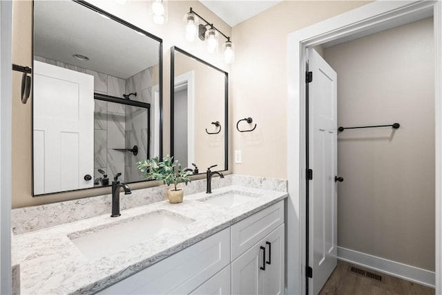 full bath with double vanity, a sink, visible vents, and a shower stall