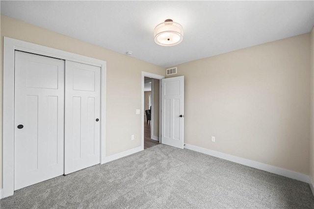 unfurnished bedroom featuring carpet, a closet, visible vents, and baseboards