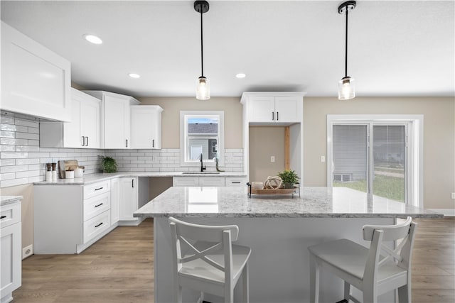 kitchen with light hardwood / wood-style floors, sink, decorative light fixtures, and decorative backsplash