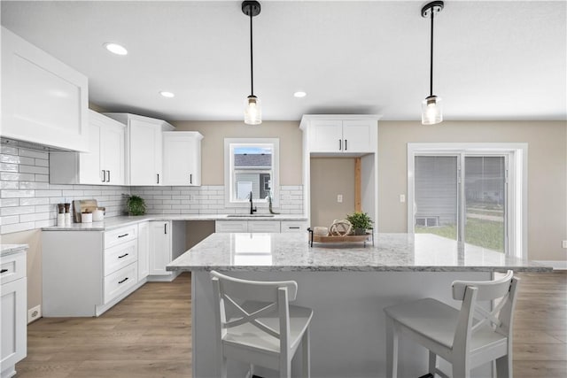 kitchen featuring white cabinetry, a center island, sink, and decorative light fixtures