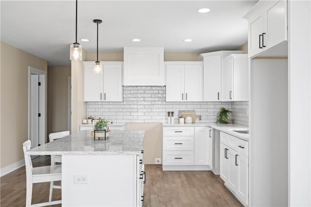 kitchen with light wood-type flooring, light stone countertops, a kitchen breakfast bar, and backsplash