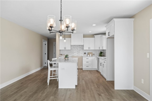 kitchen with pendant lighting, light hardwood / wood-style flooring, tasteful backsplash, and white cabinetry