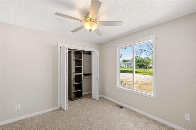 carpeted spare room featuring a healthy amount of sunlight, a textured ceiling, and ceiling fan