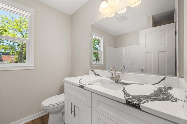 bathroom with visible vents, baseboards, toilet, walk in shower, and vanity