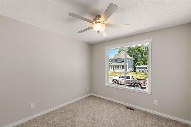 empty room with baseboards, a textured ceiling, visible vents, and carpet flooring