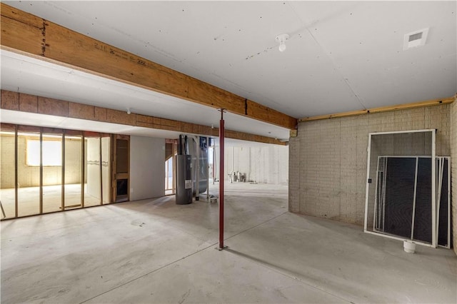 below grade area featuring brick wall, water heater, and visible vents