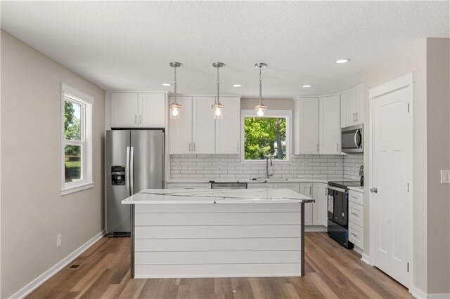 kitchen with sink, wood-type flooring, a kitchen island, and appliances with stainless steel finishes