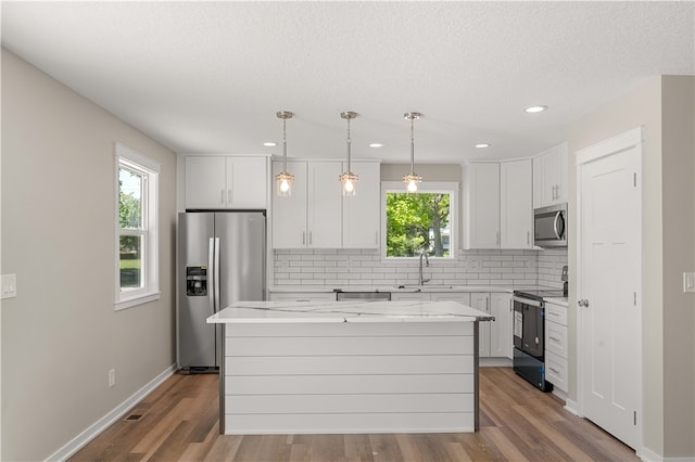 kitchen with stainless steel appliances, wood-type flooring, sink, and a center island