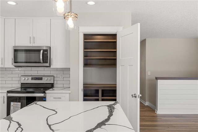 kitchen with white cabinetry, stainless steel appliances, hardwood / wood-style flooring, and pendant lighting