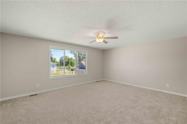 carpeted spare room featuring ceiling fan and a textured ceiling