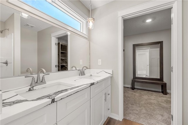 full bath with double vanity, a sink, visible vents, and baseboards