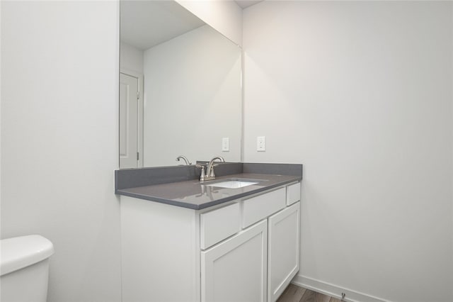 bathroom with toilet, vanity, and hardwood / wood-style flooring