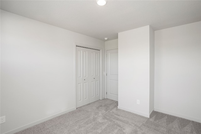 unfurnished bedroom featuring light carpet and a closet