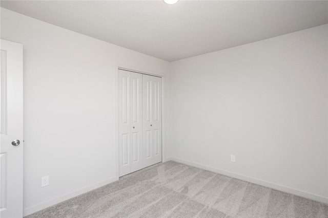 unfurnished bedroom featuring light carpet and a closet